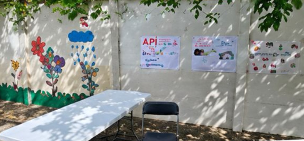 Stand de kermesse installé devant un mur décoré de dessins d'enfants